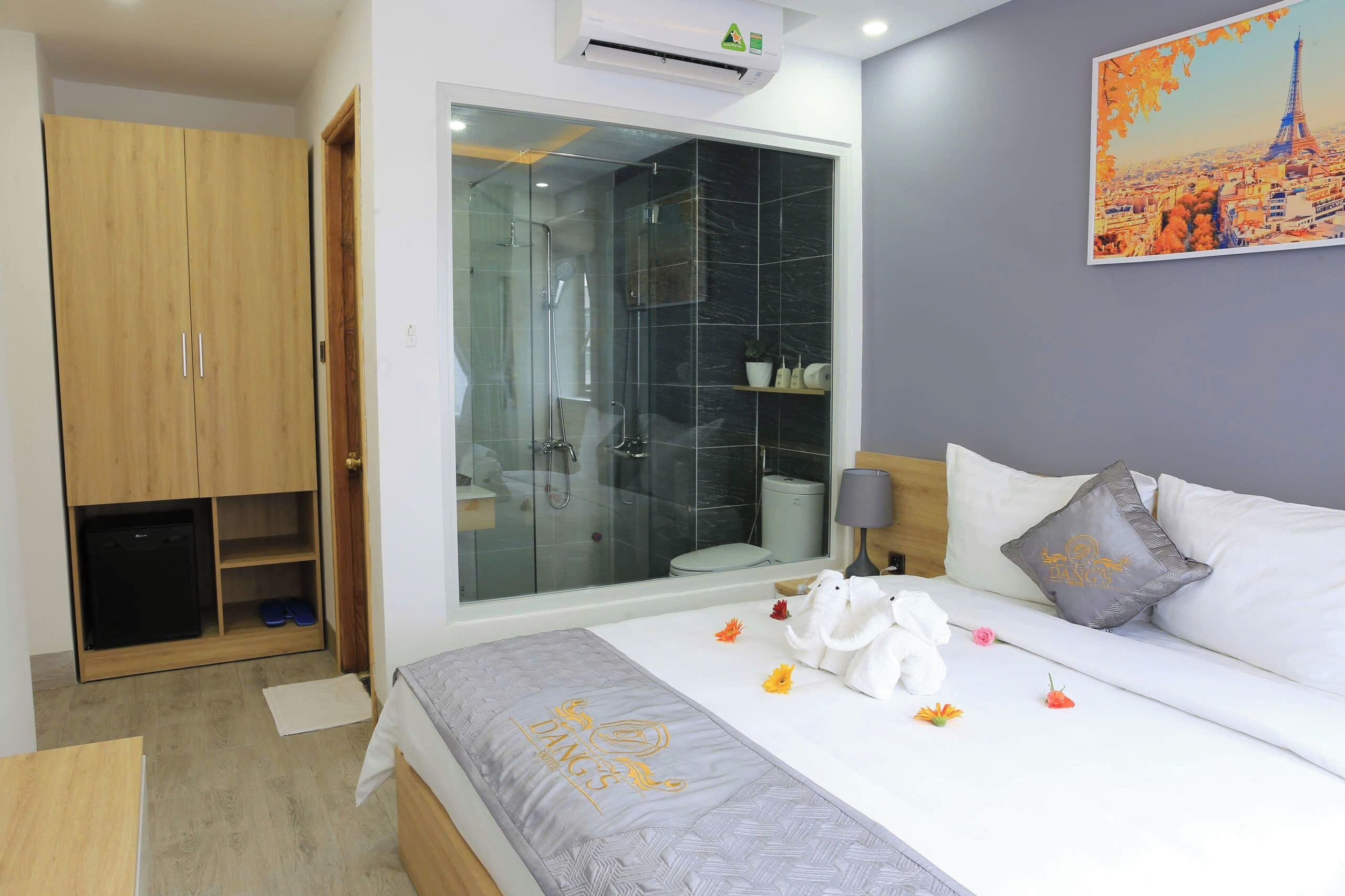 A hotel room with a bed, a wardrobe, a shower area, and a painting of a cityscape.