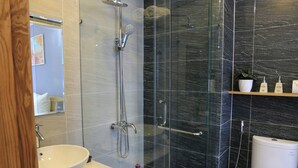 Un baño moderno con ducha de mampara de vidrio, lavabo blanco y retrete.