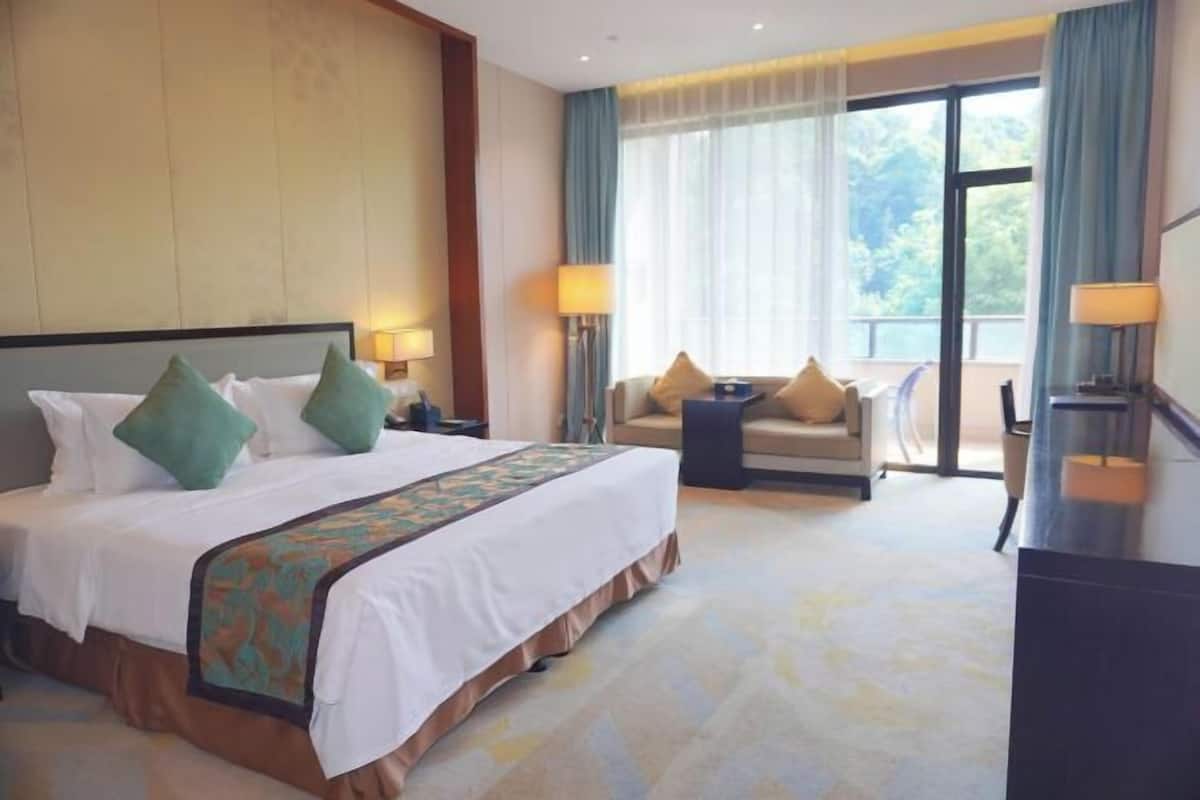 Camera d'hotel con un letto grande, un divano, una scrivania e vista sull'esterno.