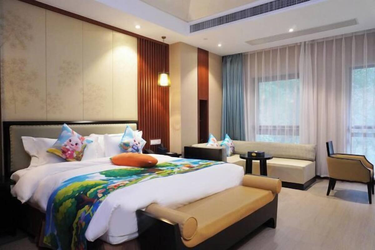 Una camera d'albergo moderna con un letto grande, un divano, un tavolino e una sedia.