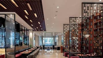A modern interior with a long dining area, seating arrangements, and a decorative partition.