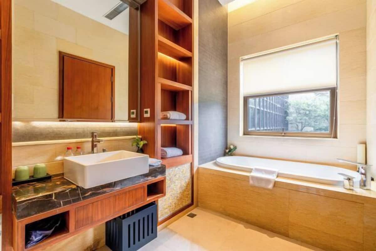 Un bagno moderno con uno specchio grande, un lavandino, una vasca da bagno e mensole integrate in legno.