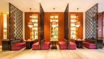 A hotel lobby with a central seating area, wooden paneling, and pendant lighting.