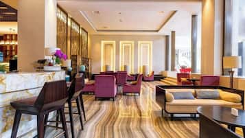 A hotel lobby with a reception desk, seating area, and a bar.