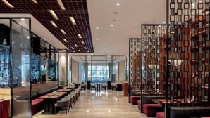 Un restaurante moderno con una barra larga, zona de estar y separadores decorativos.