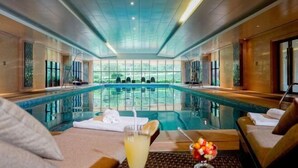Un área de piscina con sillones de descanso y una copa de bebida.