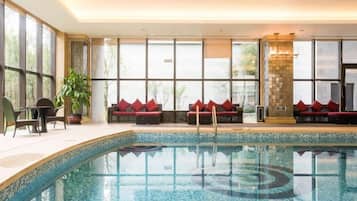 An indoor swimming pool with seating areas and large windows.