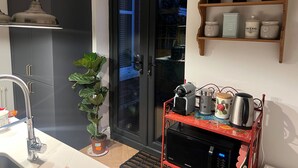 Una cocina moderna con horno empotrado, microondas y cafetera sobre un carrito rojo.