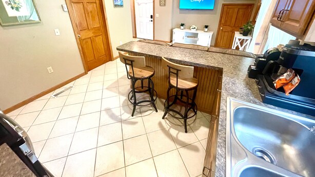 A kitchen with a bar area, a TV mounted above the counter, and a sink. - Spacious King Bed Suite at Antique Store (Wakeman)