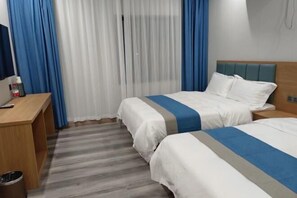 A hotel room with two beds, a wooden desk, a trash bin, and a window with blue curtains. - Lanzhou Sapphire Hotel (Lanzhou)