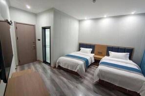 A hotel room with two beds, a wooden floor, a door, and a small table. - Lanzhou Sapphire Hotel (Lanzhou)