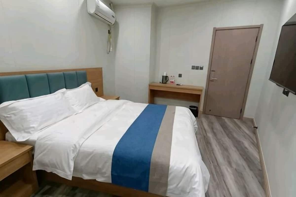 Una camera d'albergo con un letto, una scrivania, una sedia, un armadio e una televisione.