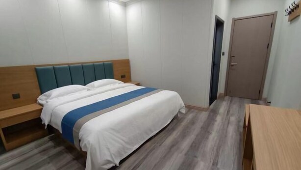 A hotel room with a bed, a wooden bench, a desk, and a door. - Lanzhou Sapphire Hotel (Lanzhou)