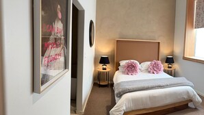 A bedroom with a bed, two bedside lamps, a poster on the wall, and a window with a view. - Boutique hotel with cocktail bar near the convention center (Tucson)