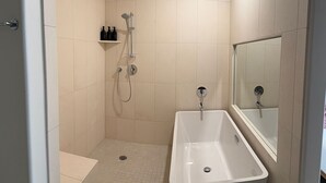 A modern bathroom with a walk-in shower, a bathtub, and a large mirror. - Boutique hotel with cocktail bar near the convention center (Tucson)