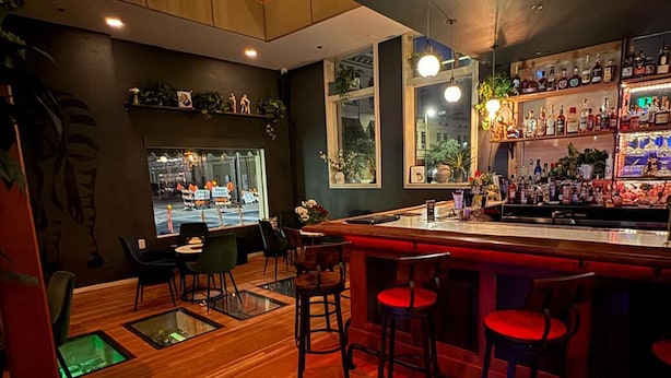 A bar area with wooden flooring, bar stools, and a well-stocked liquor shelf. - Downtown Boutique Hotel with Popular Cocktail Bar (Tucson)