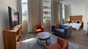 Une chambre d’hôtel avec un lit, une télévision, un canapé, une chaise et une petite table.