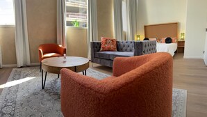 Une chambre d’hôtel avec un canapé, deux fauteuils, une table ronde et un lit.