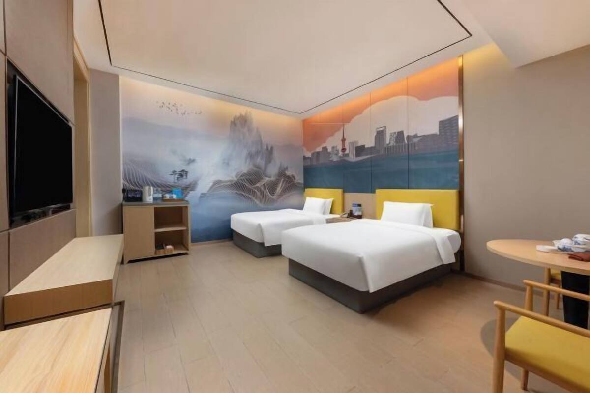 Une chambre d’hôtel avec deux lits, un bureau, une chaise et une télévision.