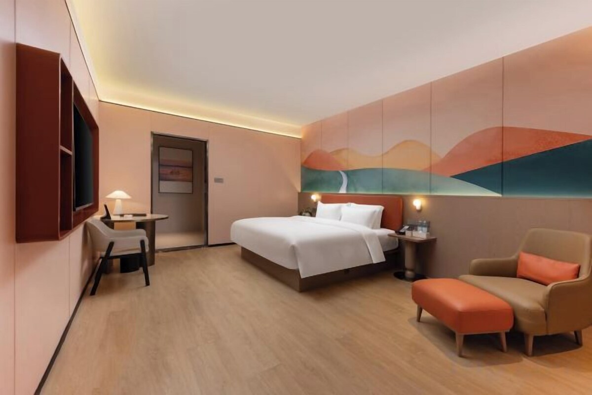 Une chambre d’hôtel avec un lit, un bureau, une chaise et un téléviseur.