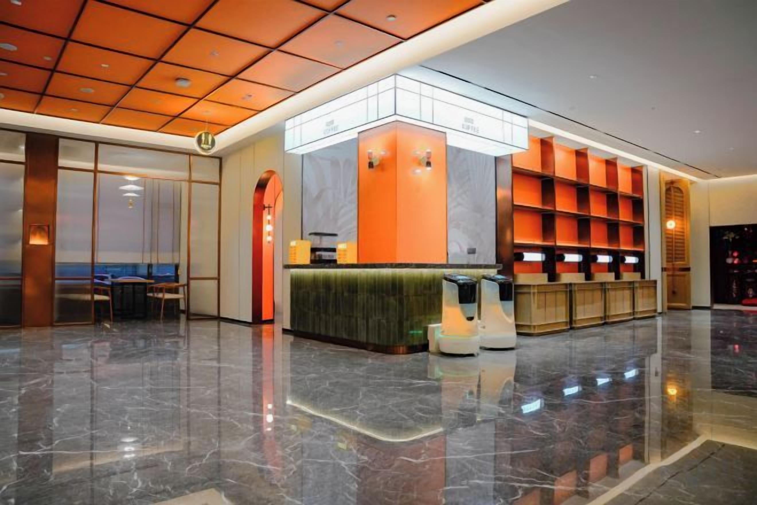 Un hall de hotel con mostrador de recepción, zona de estar y un espejo grande.