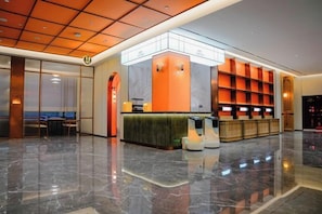 Un hall d’hôtel comprenant un comptoir d’accueil, un espace salon et un grand miroir.