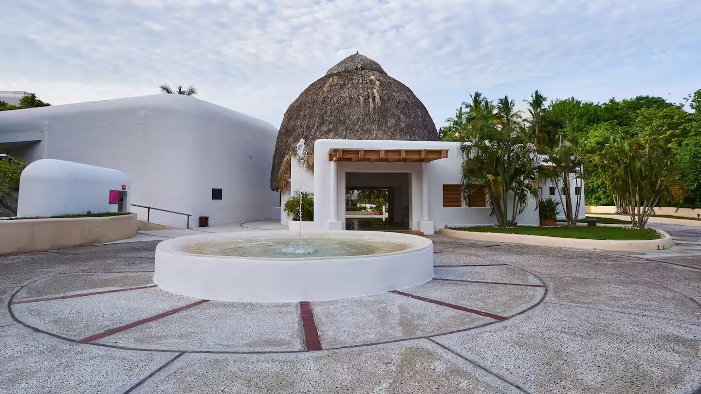 Un bâtiment moderne doté d’une façade incurvée originale et d’une structure surmontée d’un toit de chaume.