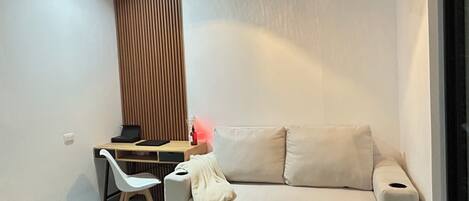 Una sala de estar moderna con un sofá, un escritorio con una silla y una lámpara colgante.