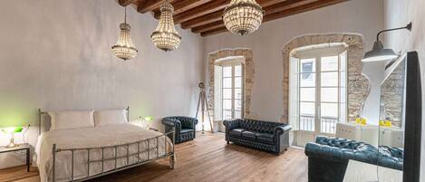 A spacious bedroom with a large bed, two sofas, and a wooden floor.