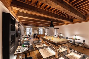 Un comedor amplio con una gran mesa de madera, múltiples sillas y un techo alto con vigas a la vista.