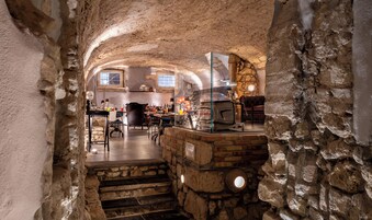 A stone-walled interior with a kitchen area, dining table, and seating.