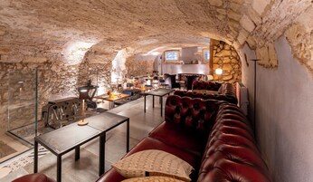 A cozy interior with stone walls, leather seating, and a dining area with tables and chairs.