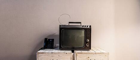 A vintage television on top of a wooden crate with the inscription "Birraria Ichnusa Cagliari".