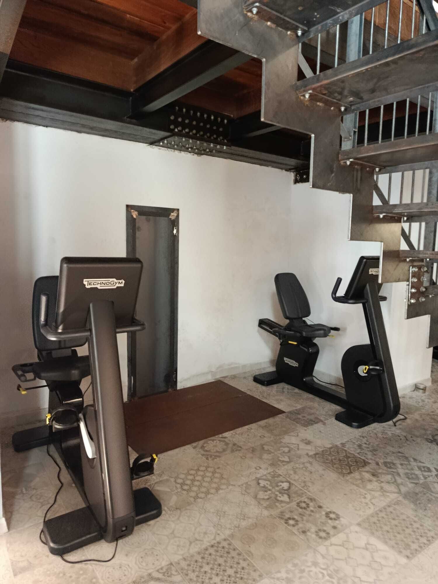 A home gym with a treadmill, elliptical, and stationary bike.