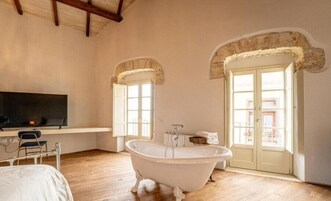A spacious bathroom with a freestanding bathtub, a television, and a window with a view of the outside.