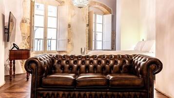 A room with a leather sofa, wooden flooring, and exposed wooden beams.