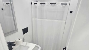 A small, modern bathroom with a toilet, sink, and mirror.