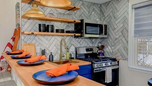 Eine moderne Küche mit einer Holztheke, eingebauten Geräten und einer Rückwand mit Fischgrätenmuster.