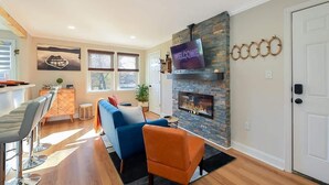 Ein modernes Wohnzimmer mit Kamin aus Stein, darüber montiertem Fernseher und einem blauen Sofa.