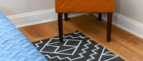 A room with a bed, a patterned rug, and an orange chair.
