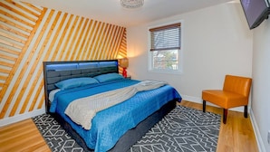 A bedroom with a bed, a chair, a window, and a TV. - Treehouse Suite | King BR | Spa bath | Calm Energy (Parkville)
