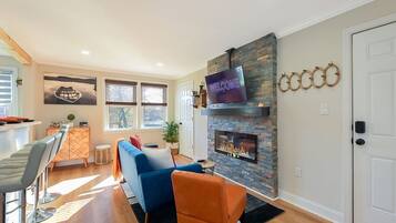 A living room with a fireplace, a television mounted above it, and a sofa.