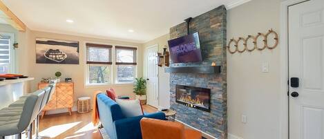 Una sala de estar con chimenea, un televisor montado arriba y un sofá.