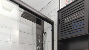 A shower area with a handheld showerhead, a toilet, and a ventilation unit. - Treehouse Suite | King BR | Spa bath | Calm Energy (Parkville)