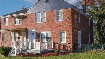 A two-story brick house with a front porch and a small front yard.