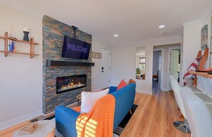 Una sala de estar moderna con chimenea de piedra, un televisor montado y un sofá azul.