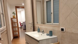 A modern bathroom with a large sink, a mirror, and a towel rack.