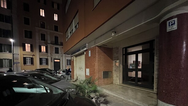 A parking area with multiple cars, a building entrance, and a sign indicating a parking area.