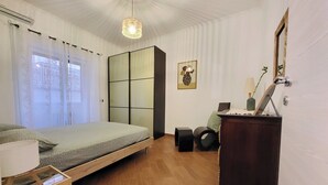 A bedroom with a bed, a desk, a chair, a wardrobe, and a hanging light fixture.