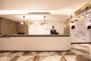 A reception desk with a modern design, a person standing behind it, and a patterned floor.